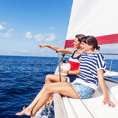 Two woman sitting on the edge of a boat pointing at something