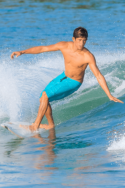 Young man cutting through the water on his surf board