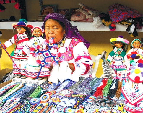 Huicholes woman showing her handicrafts at a market table