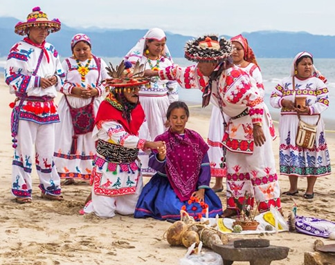 Group of colourfully dressed Huicholes people on the beach