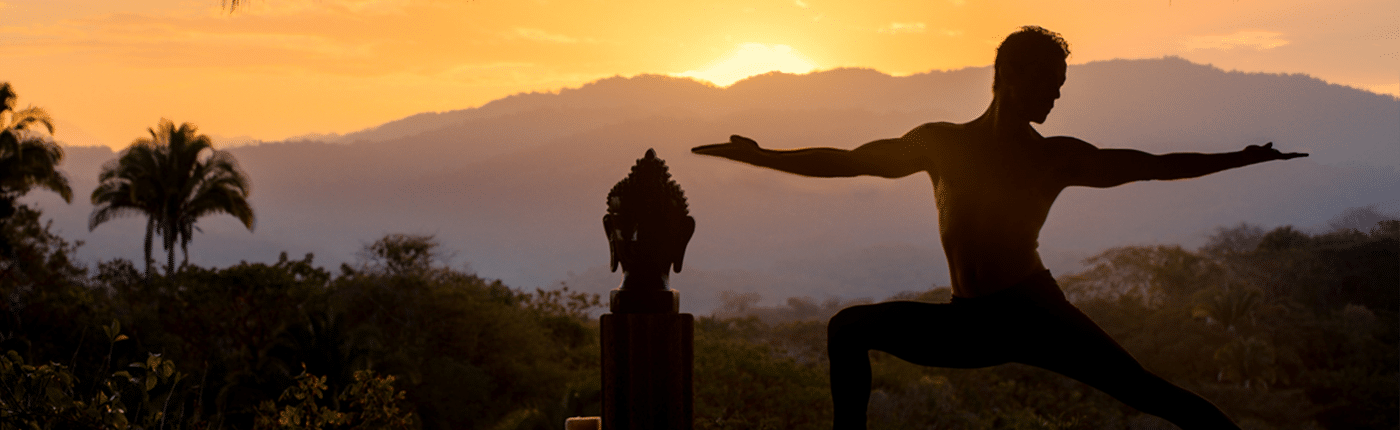 Man at sunrise doing yoga next to temple figure