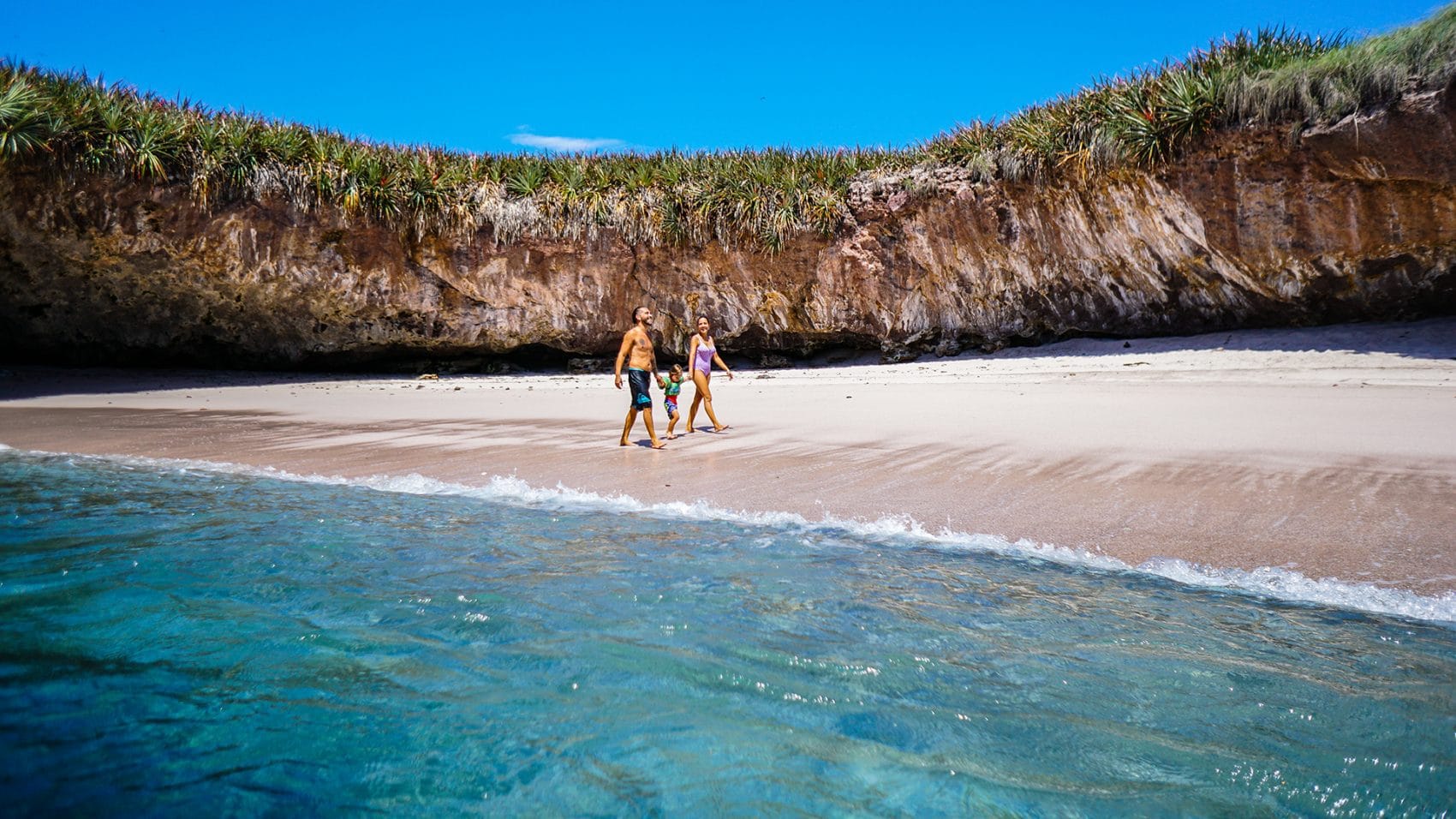 Couple walking with child on Marietas beach in Riviera Nayarit